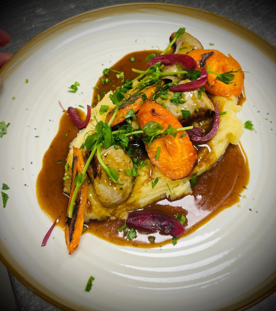 Plat de purée de pommes de terre, crevettes, carottes et sauce brunie, garni d'herbes.