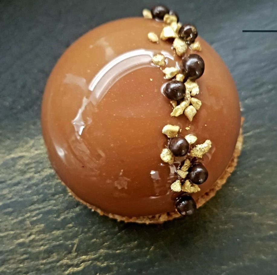 Gâteau rond au chocolat avec un glaçage brillant et garniture de noix et de café.